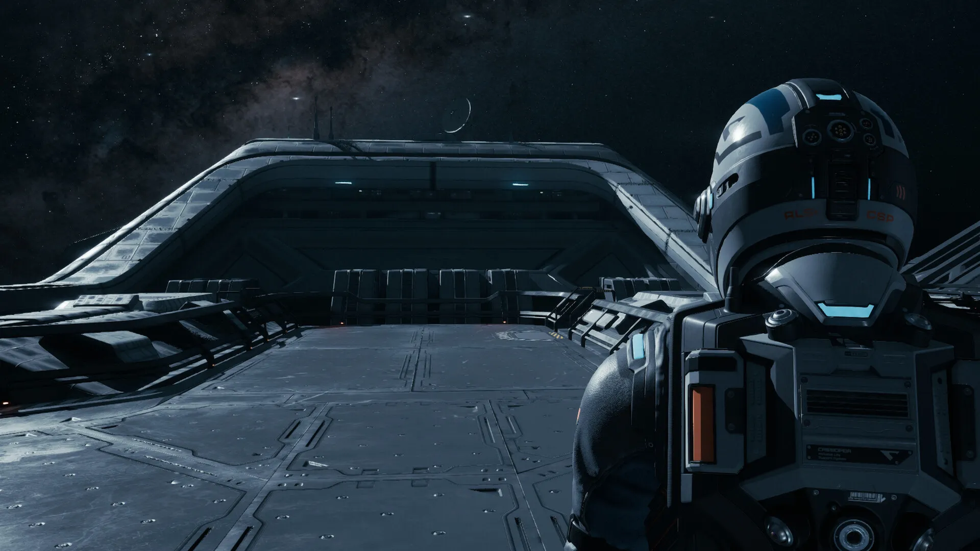 An armoured crew member looking out across a ship's hangar.