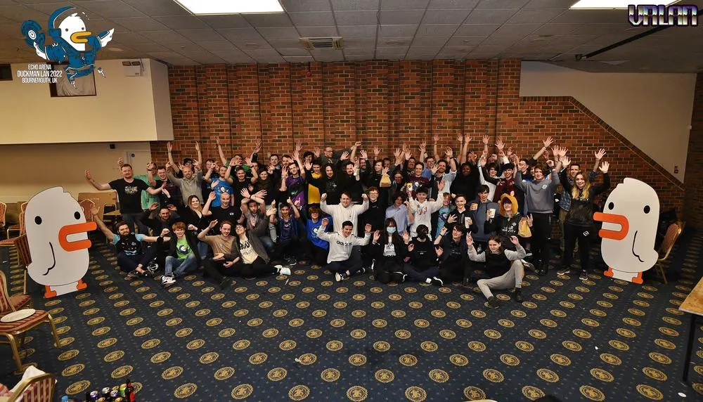 The whole Duckman LAN 2022 crowd posing with their arms raised.