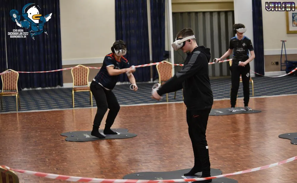 Two players in VR headsets mid-match in the roped-off play area.